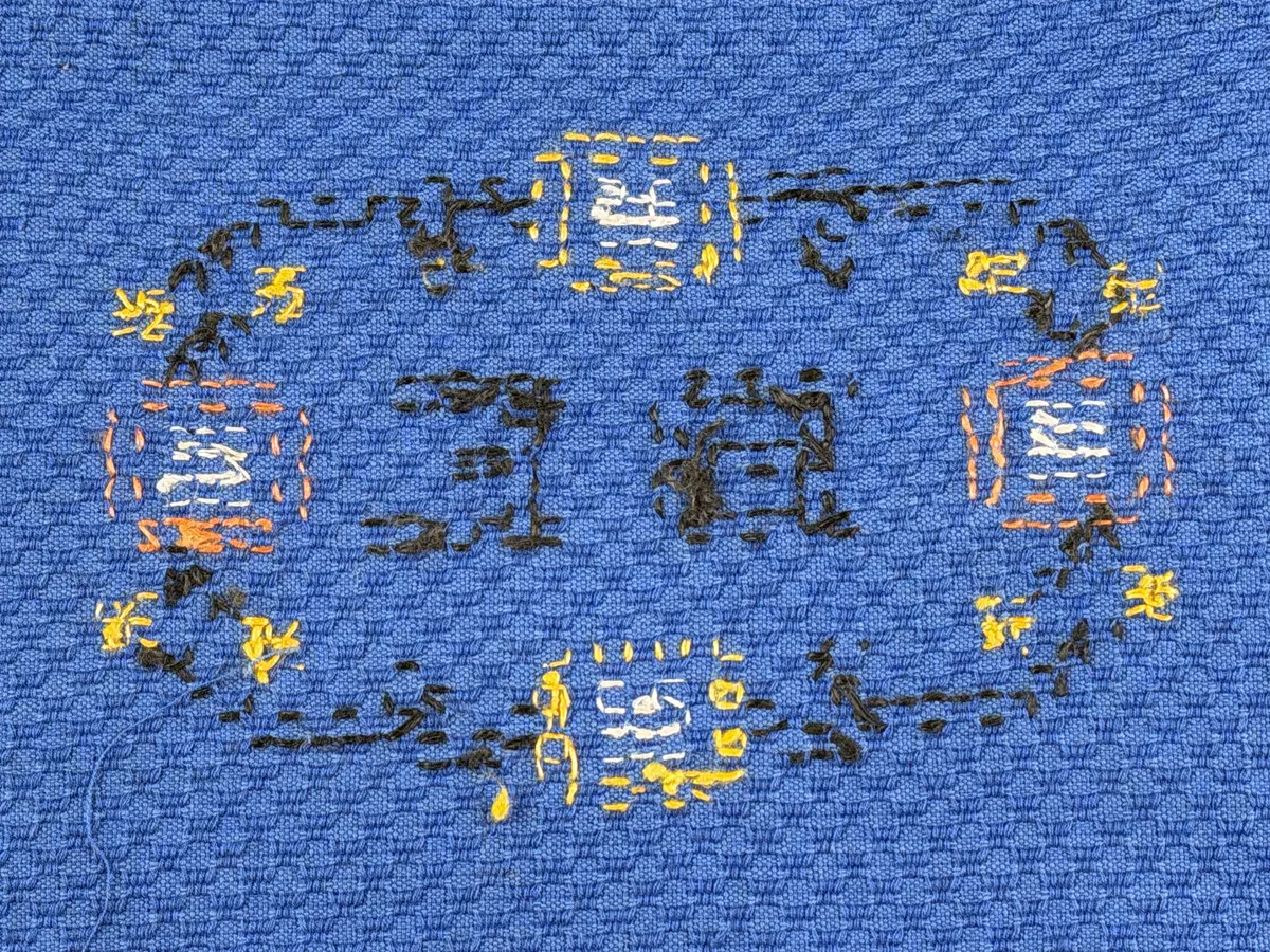 Tygpåse gjord av bomullsväv i sålldräll och broderi utfört med lingarn i korsstygn. Påsens öppning har en dragsko, 22mm bred dubbelvikt sydd med smygstygn, för förslutning med ett band. Påsen är hopsydd med vändsöm och raksöm.