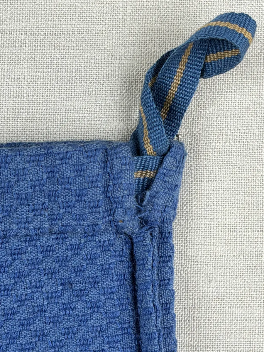 Tygpåse gjord av bomullsväv i sålldräll och broderi utfört med lingarn i korsstygn. Påsens öppning har en dragsko, 22mm bred dubbelvikt sydd med smygstygn, för förslutning med ett band. Påsen är hopsydd med vändsöm och raksöm.