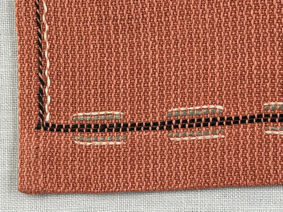 Tablett gjord av halvlinne i liksidig korskypert och broderi utfört med 2-trådigt lingarn i trädsöm. 
Dukens kortsidor har 18mm breda fållar och långsidorna 7mm, vilka är sydda med smygstygn. 