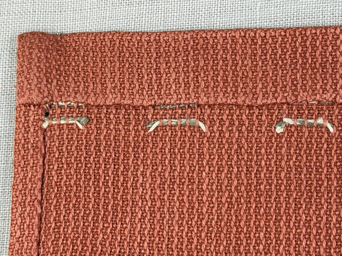 Tablett gjord av halvlinne i liksidig korskypert och broderi utfört med 2-trådigt lingarn i trädsöm. 
Dukens kortsidor har 18mm breda fållar och långsidorna 7mm, vilka är sydda med smygstygn. 