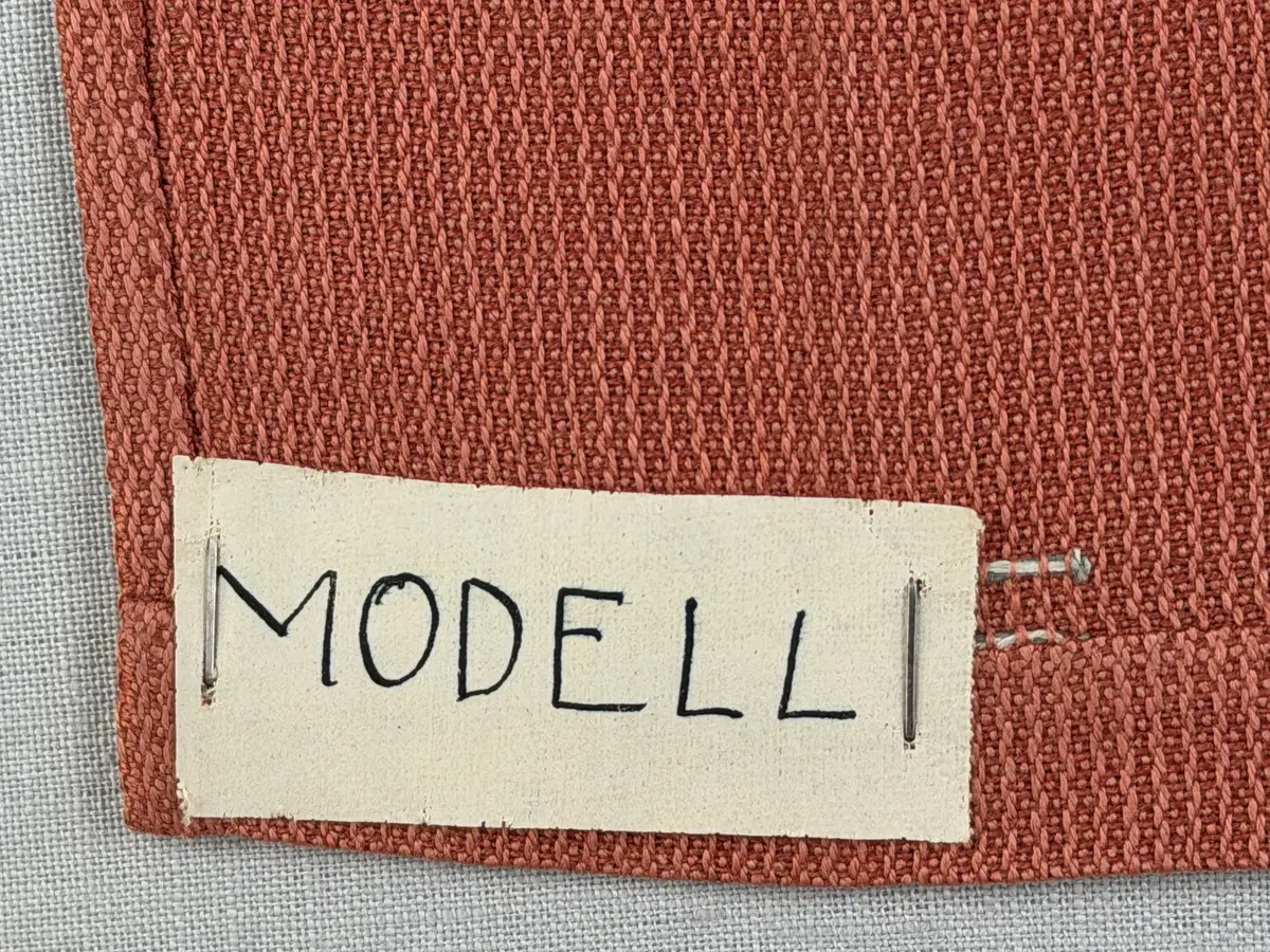 Tablett gjord av halvlinne i liksidig korskypert och broderi utfört med 2-trådigt lingarn i trädsöm. 
Dukens kortsidor har 18mm breda fållar och långsidorna 7mm, vilka är sydda med smygstygn. 