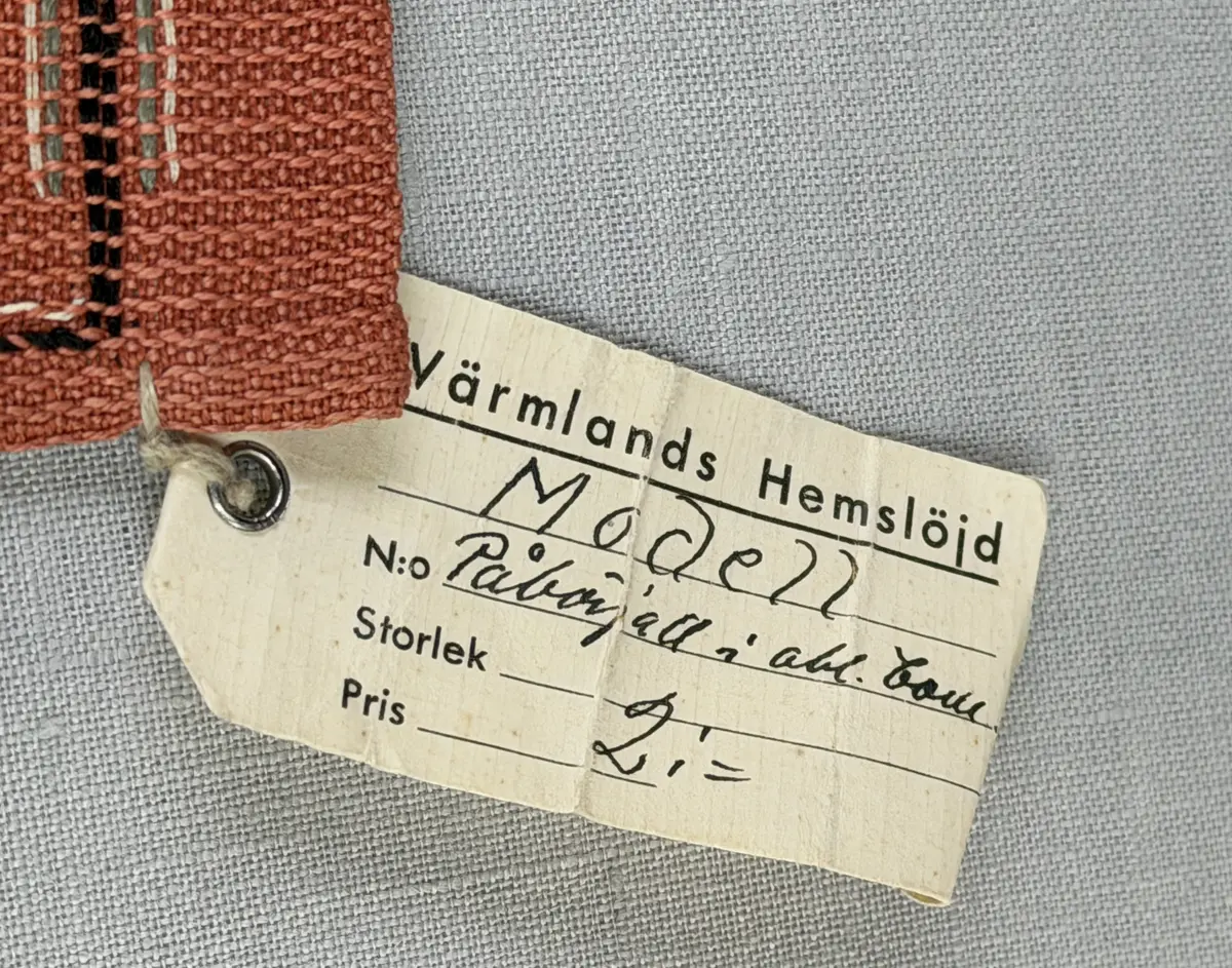 Tablett gjord av halvlinne i liksidig korskypert och broderi utfört med 2-trådigt lingarn i trädsöm. 
Dukens kortsidor har 18mm breda fållar och långsidorna 7mm, vilka är sydda med smygstygn. 