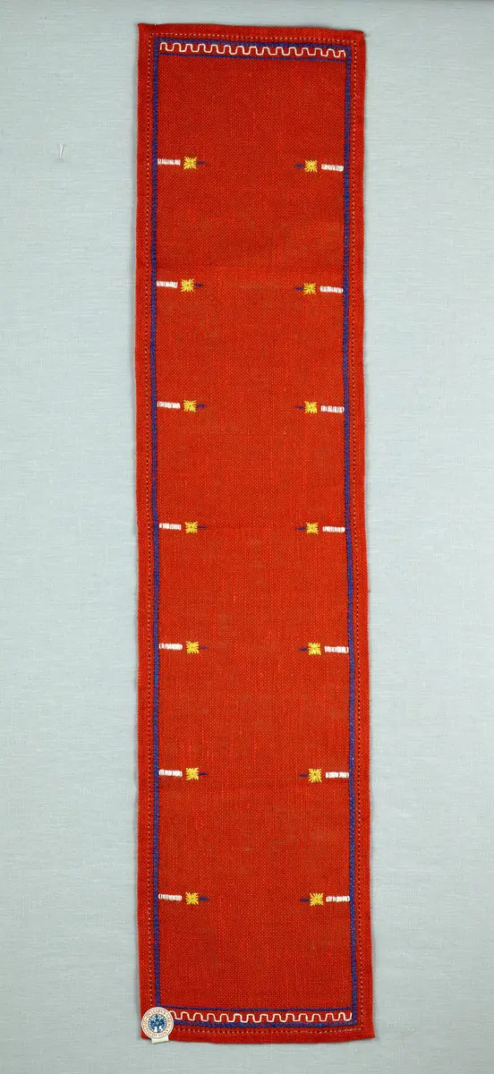 Jullöpare gjord av linneväv med 7tr/cm i tuskaft och broderi utfört med lingarn i stjälksöm, rutsöm, plattsöm samt korsstygn. 
Löparen är inramad med en korsstygns rad och kanterna har 9mm breda fållar runt om fastsydda med en halv hålsöm plus sneda hörn, vilka är sydda med kaststygn. 