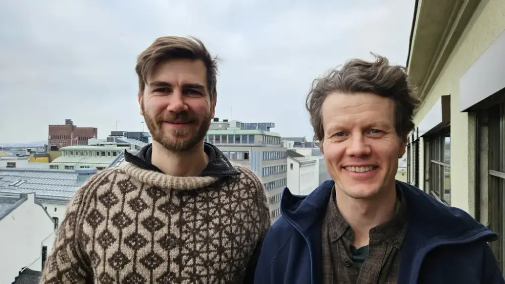 to menn står på ein terrasse med utsikt over Oslo