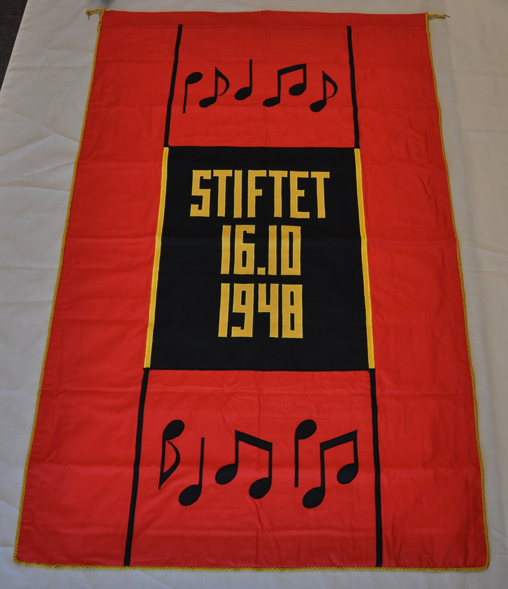 Faneduken er av bomull. Rød, sort, gul. Rød bunn, applikert sort og gul tekst og dekor. Løpegang øverst, gul snor langs alle fire kanter. Forsiden har noter som dekor. Tekst forside: "Tonevell Halden". Baksiden har noter som dekot. Tekst bakside: "Stiftet 16.10.1948. 