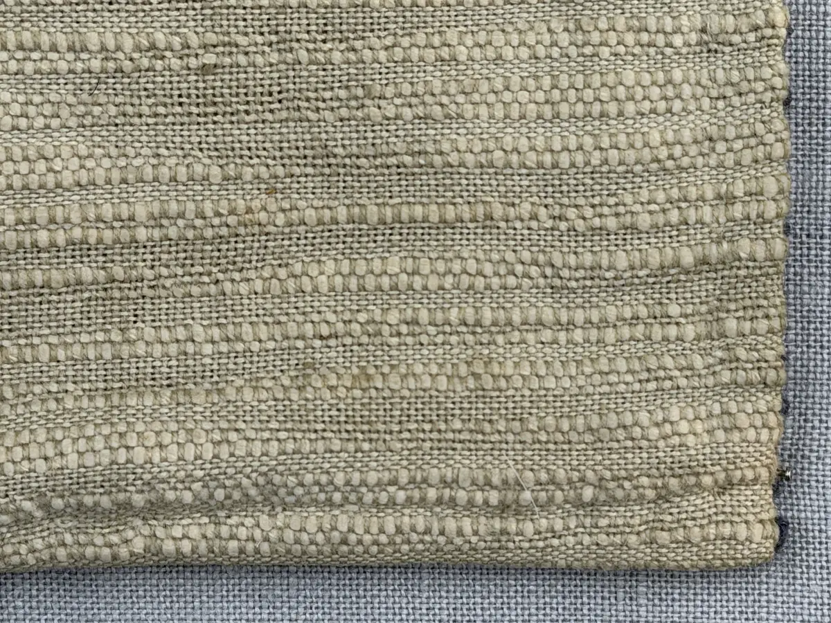 Kuddvar, gjord av tuskaftsväv i bomull och cottolin, som är dekorerad på framsidan med broderi utfört med ullgarn och splendolin i stjälksöm, kedjesöm, bottensöm, läggsöm, trädsöm, knutar samt ryaknutar. Kuddvaret är hopsytt med raksöm, därefter ett varv med stjälksöm cirka 1cm in från ytterkanten på kuddvarets rätsida.