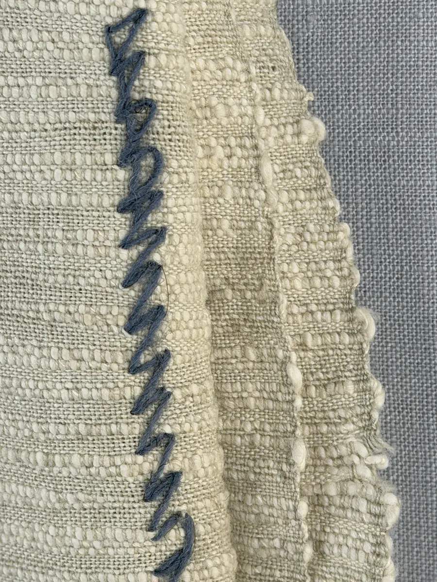 Kuddvar, gjord av tuskaftsväv i bomull och cottolin, som är dekorerad på framsidan med broderi utfört med ullgarn och splendolin i stjälksöm, kedjesöm, bottensöm, läggsöm, trädsöm, knutar samt ryaknutar. Kuddvaret är hopsytt med raksöm, därefter ett varv med stjälksöm cirka 1cm in från ytterkanten på kuddvarets rätsida.