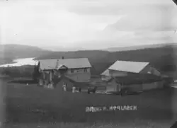 Oversiktsfoto av gård, merket «Bakken. Nyplassen». Mann med 