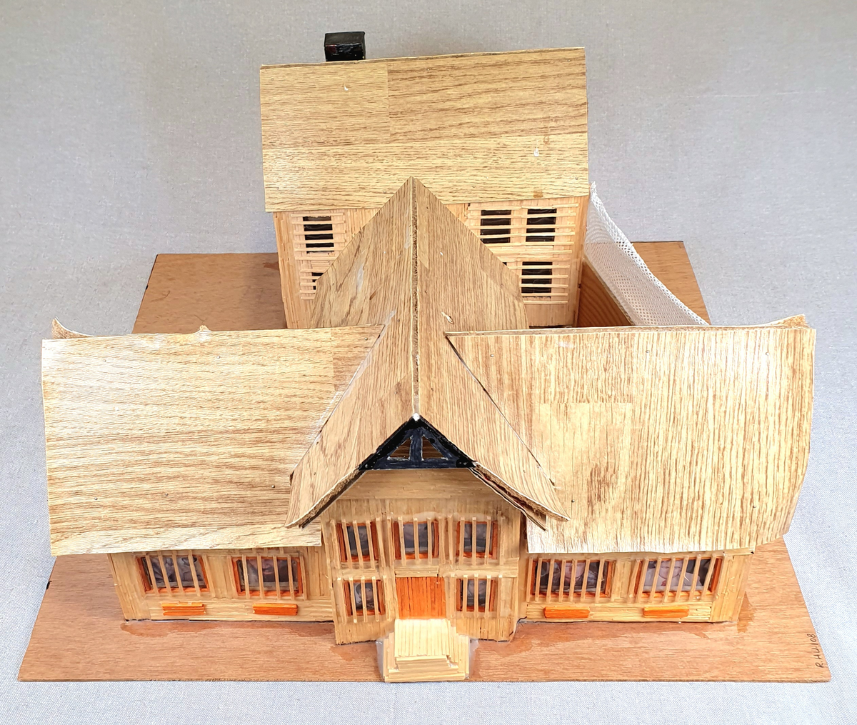 Målestokkmodell av Molde fengsel limt til en treplate. Bygget av finerplater, fyrstikker, papp, vinylbelegg, plast og tekstil. I vinduene i det fremste bygget er det bilder av forskjellige folk, blant annet hijackere tilknyttet 9/11 som var de eneste bildene med navn under.