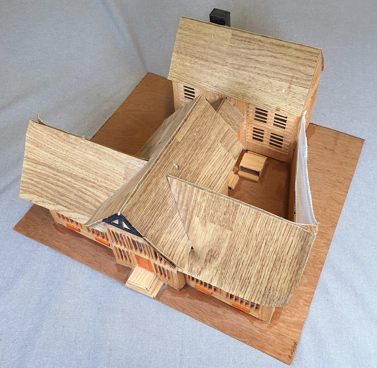 Målestokkmodell av Molde fengsel limt til en treplate. Bygget av finerplater, fyrstikker, papp, vinylbelegg, plast og tekstil. I vinduene i det fremste bygget er det bilder av forskjellige folk, blant annet hijackere tilknyttet 9/11 som var de eneste bildene med navn under.