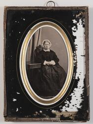 Portrett av kvinne (Fru Klem) som sitter ved bord. Bildet er