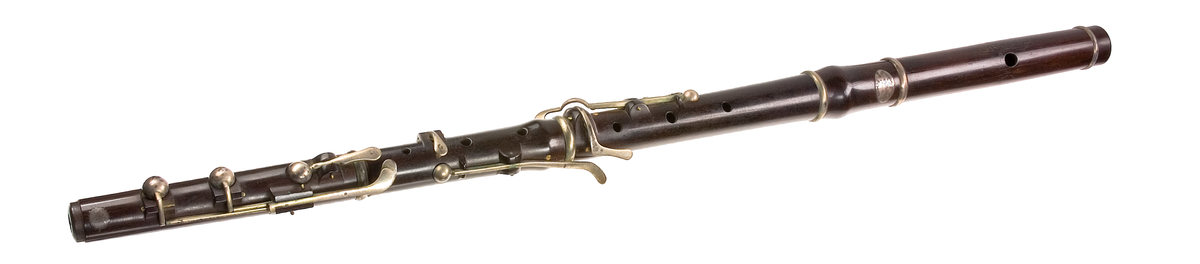 Tvärflöjt i ebenholts med silverringar. Nedersta ringen saknas. 5 delar. Konisk form. Sprickor i munstycke och päron. Stämpel på oval silverplatta på päronet. C-fot. 8 klaffar i silver med bocklagring och kulformade plattor. 