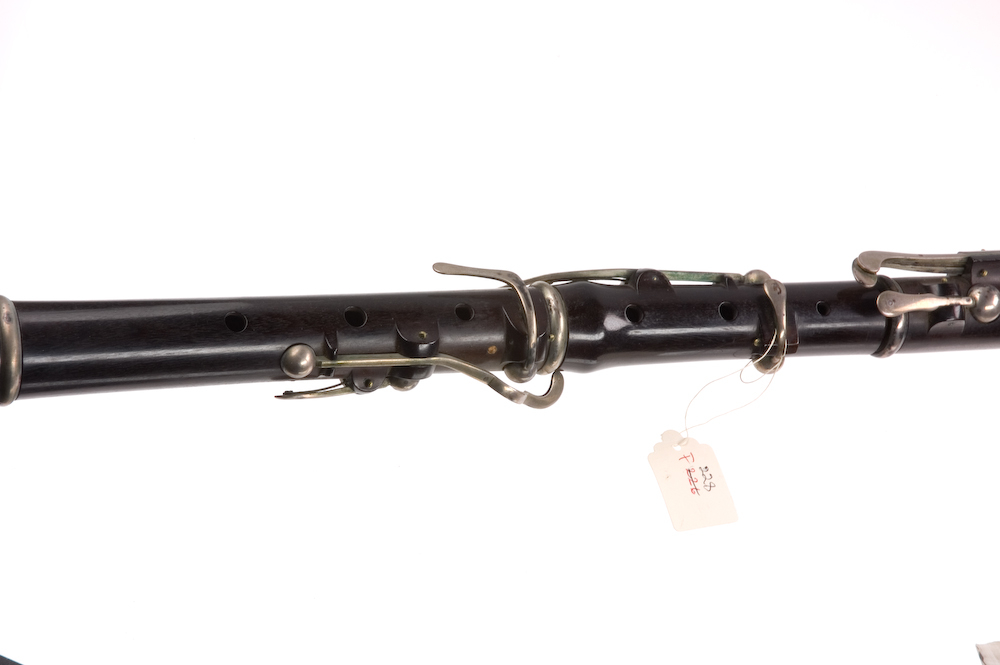Tvärflöjt i ebenholts med silverringar. Nedersta ringen saknas. 5 delar. Konisk form. Sprickor i munstycke och päron. Stämpel på oval silverplatta på päronet. C-fot. 8 klaffar i silver med bocklagring och kulformade plattor. 