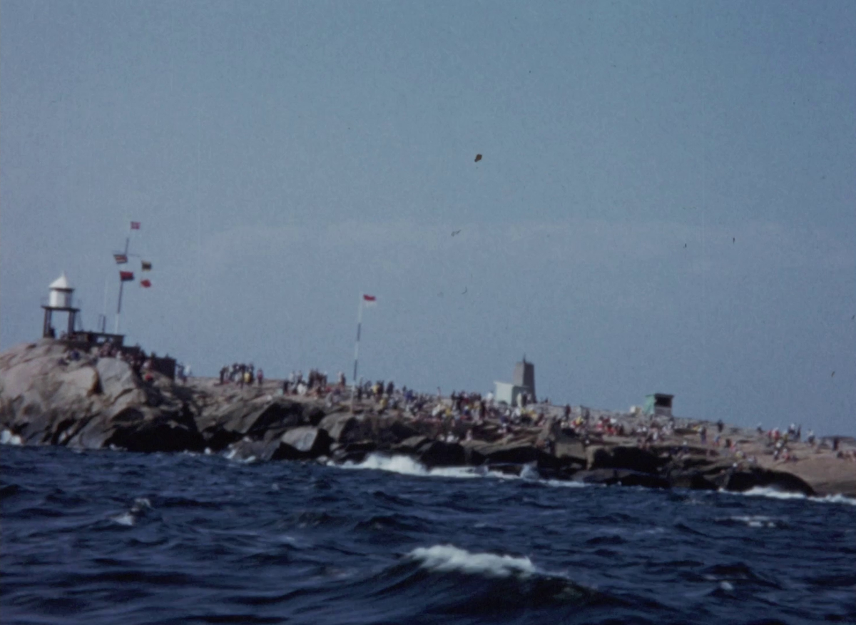 Färgfilm ur Upsala segelsällskaps (USS) arkiv från kappseglingar vid Nordre Garnholmen, söder om Hankø i yttre Oslofjorden. De inledande klippen ur filmen är skadade så att bilden suddas ut med vertikala linjer. Senare i filmen förekommer även andra typer av skador.


Drakbåtar, sexor, åttor, tior, knarrar och skärgårdskryssare av olika klasser seglar på öppet vatten. Flera kvinnor ser på seglingen från olika båtar; någon har en hund med sig och en annan bär skärmmössa med märke från Göteborgs Kungliga Segelsällskaps (GKSS). Fler åskådare färdas i en motoreka.


Närmare land ligger kungaskeppet NORGE ankrat. En av skeppsbåtarna är sjösatt och ligger intill skeppets skrov. 


Flera segelbåtar ur flera olika klasser rundar märken under kappseglingar. Även lastfartyg och fiskebåtar passerar tävlingsområdet. En vit motorseglare flaggar med den norska statsflaggan, som utsirats med kung Olov V:s monogram. På Nordre Garnholmens klippor har publik samlats för att se på tävlingarna. Vid öns södra udde står en fyr och mitt på ön skymtar Johan Ankers minnesmonument. Anker var en norsk båtkonstruktör och kappseglare som tillsammans med Olov V vann OS-guld i segling 1928.