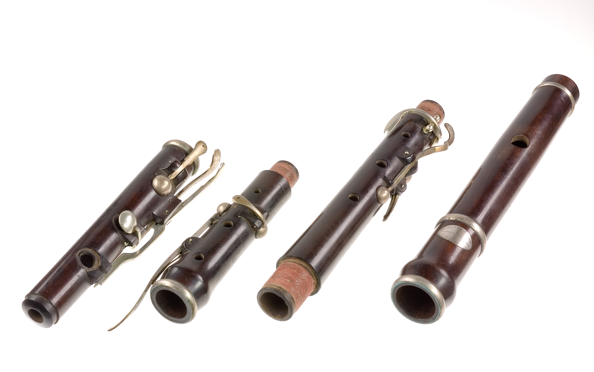 Tvärflöjt i ebenholts med silverringar och C-fot. 5 delar. Konisk form och svarvade vulster. Stämpel på oval silverplatta på päronet. C-fot. 8 klaffar med bocklagring, varav 1 klaff är trasig. 1 bocklagring är ersatt med kullagring.