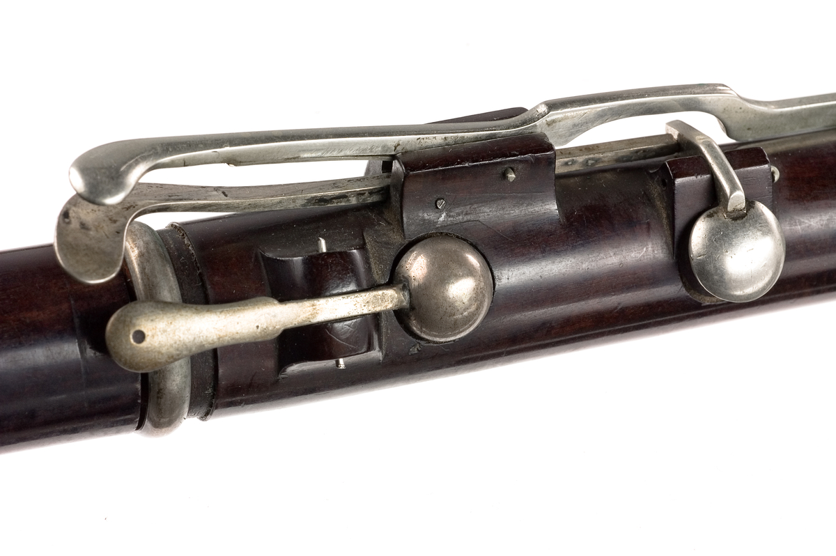 Tvärflöjt i ebenholts med silverringar och C-fot. 5 delar. Konisk form och svarvade vulster. Stämpel på oval silverplatta på päronet. C-fot. 8 klaffar med bocklagring, varav 1 klaff är trasig. 1 bocklagring är ersatt med kullagring.