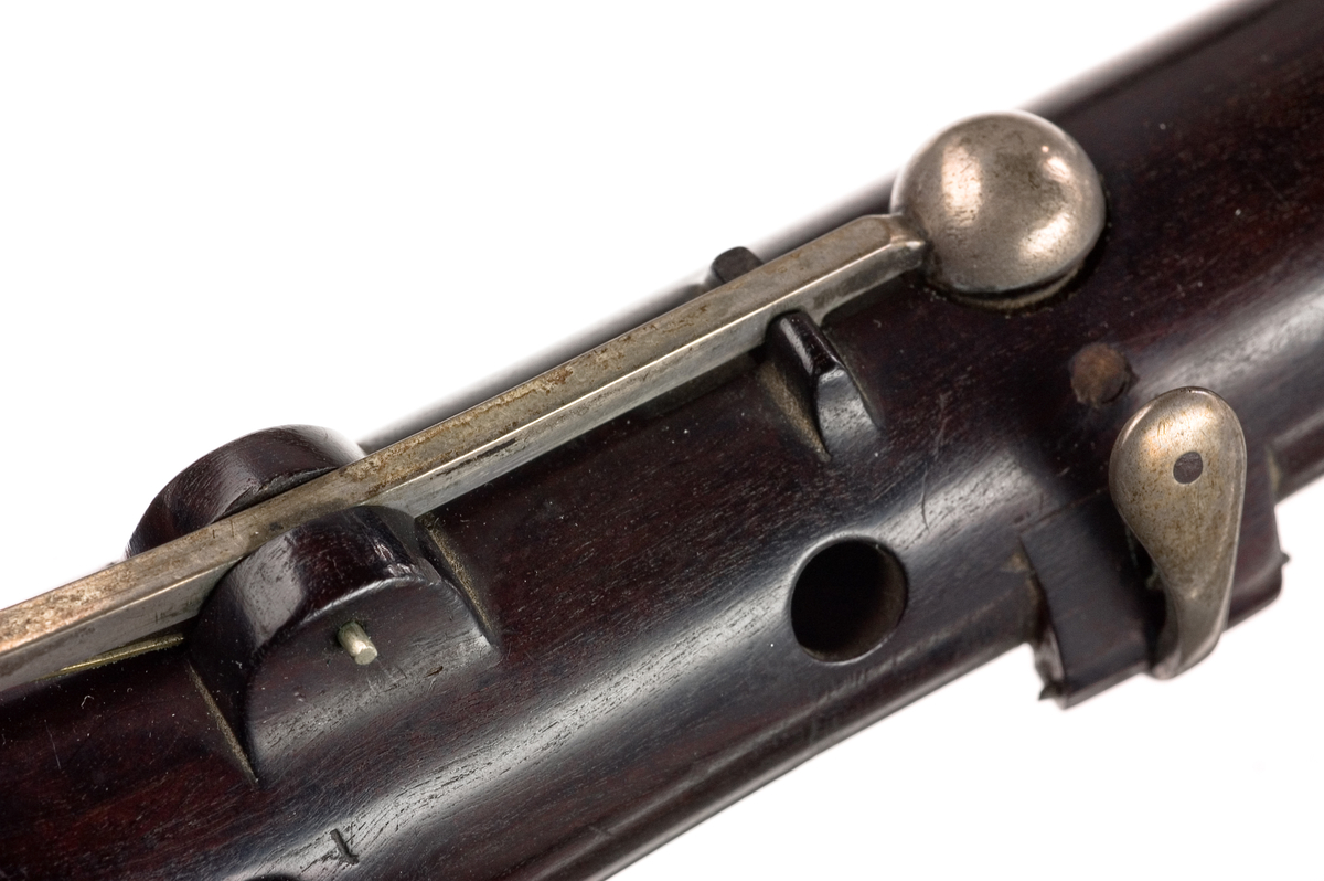 Tvärflöjt i ebenholts med silverringar och C-fot. 5 delar. Konisk form och svarvade vulster. Stämpel på oval silverplatta på päronet. C-fot. 8 klaffar med bocklagring, varav 1 klaff är trasig. 1 bocklagring är ersatt med kullagring.