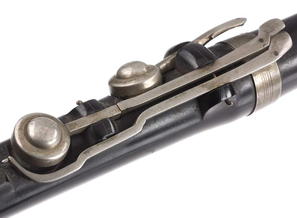 Tvärflöjt i ebenholts med ringar av silver. Nedersta ringen saknas. 5 delar. Sprickor i munstycke och päron. C-fot. 8 klaffar med bocklagring och tjocka runda plattor med kulformade toppar. Delar av lägsta klaffen och dess lagring saknas.