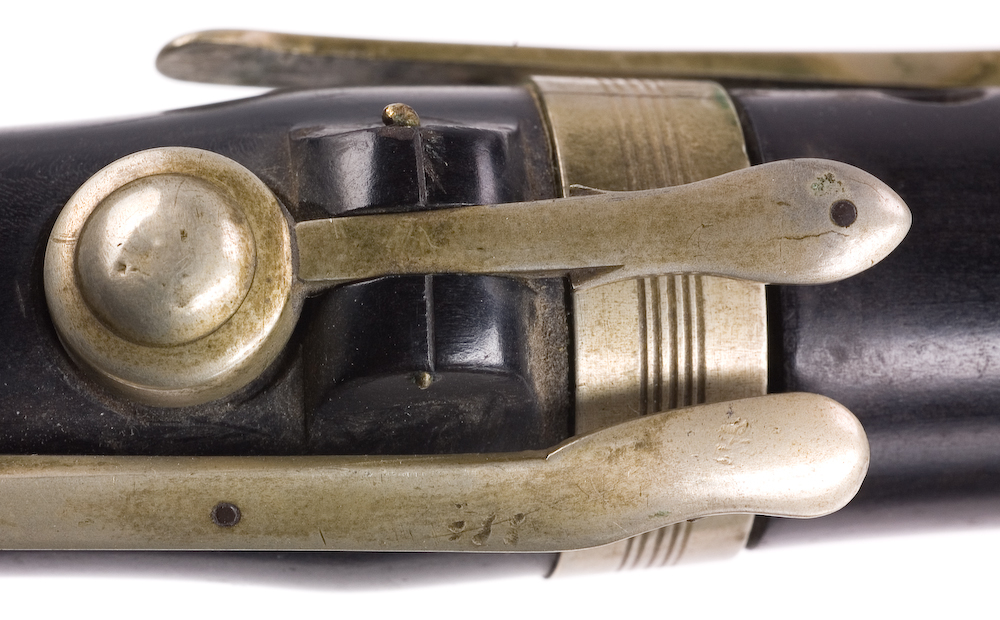 Tvärflöjt i ebenholts med ringar av silver. Nedersta ringen saknas. 5 delar. Sprickor i munstycke och päron. C-fot. 8 klaffar med bocklagring och tjocka runda plattor med kulformade toppar. Delar av lägsta klaffen och dess lagring saknas.