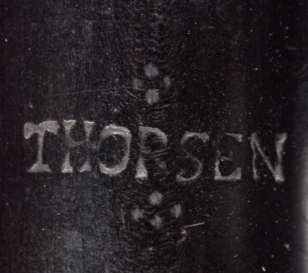 Tvärflöjt i ebenholts med ringar av silver. Nedersta ringen saknas. 5 delar. Sprickor i munstycke och päron. C-fot. 8 klaffar med bocklagring och tjocka runda plattor med kulformade toppar. Delar av lägsta klaffen och dess lagring saknas.