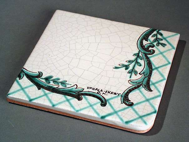 15 st kakelplattor till bordskiva, av gult lergods med målad dekor bestående av bladslingor och rutor i grönt och svart samt kantbård mot grå vit krackeléglasyr, de fyra hörnplattorna har rundade hörn. På baksidan i relief: 1045 8 UE.