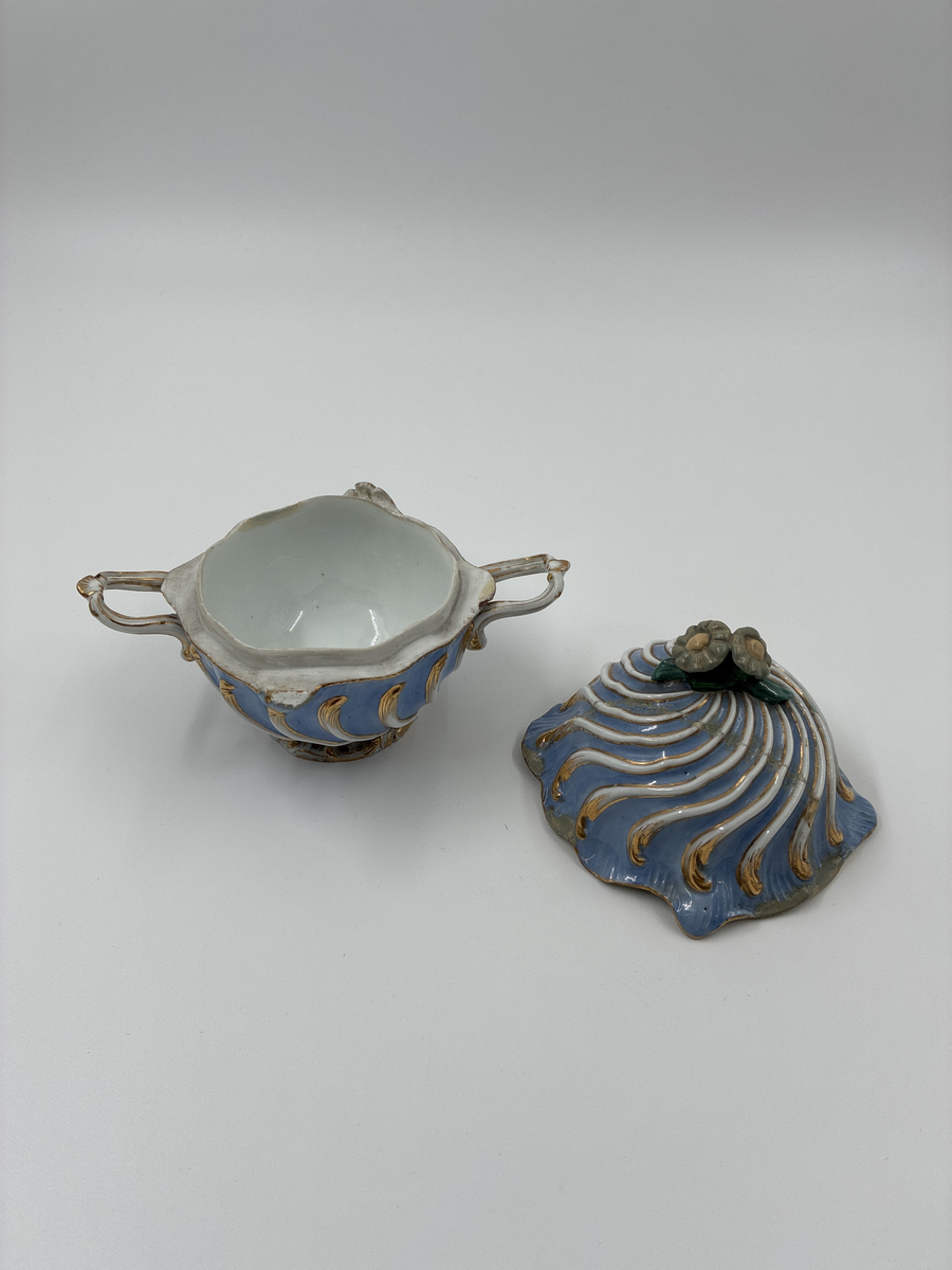 Bonbonjär med två handtag samt lock dekorerad med två blommor. Blåglaserat porslin med gulddekor. Från Meissen, Tyskland.