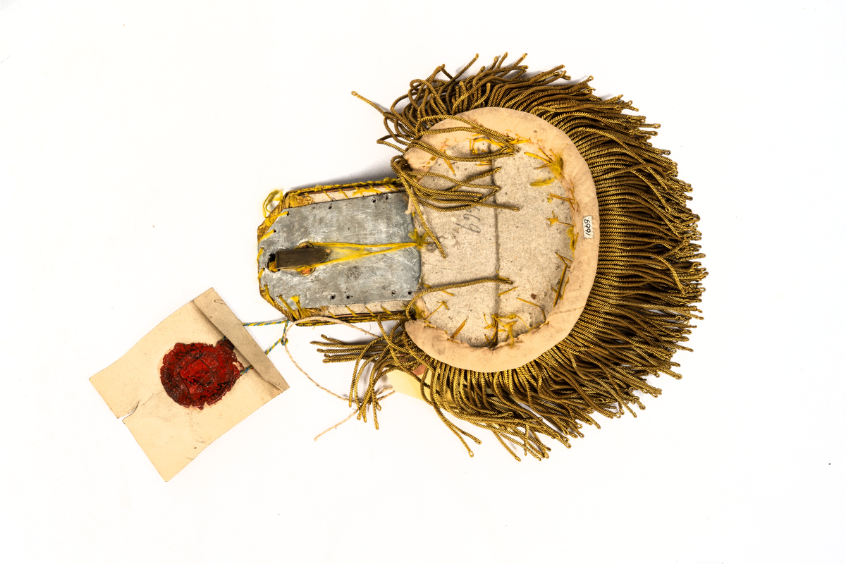 Epåletter M/1844. Klaff av guldtyg av guldtyg med trådsmala buljoner av guld samt liten ankarknapp. Ofodrad.
