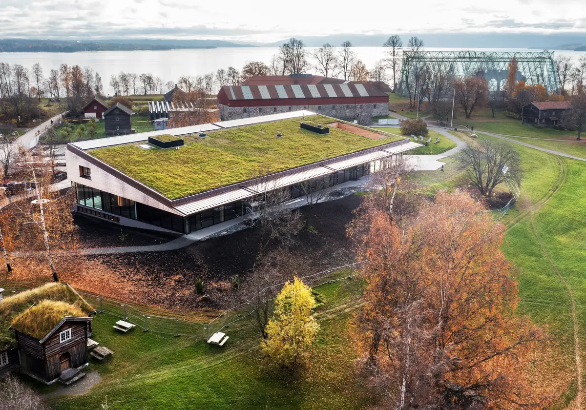 Dronebilde av Domkirkeodden med nybygget Shelter i forgrunnen. I bakgrunnen sees Storhamarlåven og domkirkeruinen med vernebygg i glass over. Mjøsa lengst bak.