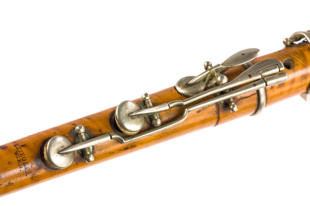 Tvärflöjt i buxbom med silverringar. 5 delar. C-fot. Kvadratiskt anblåsningshål. Tydliga märken efter användning vid anblåsnings- och fingerhål. 10 klaffar med kullagring, fästa i fastskruvade plattor. Klaffarnas plattor är runda. Klaffhålen har monterade metallrör.