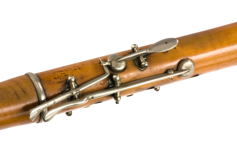 Tvärflöjt i buxbom med silverringar. 5 delar. C-fot. Kvadratiskt anblåsningshål. Tydliga märken efter användning vid anblåsnings- och fingerhål. 10 klaffar med kullagring, fästa i fastskruvade plattor. Klaffarnas plattor är runda. Klaffhålen har monterade metallrör.