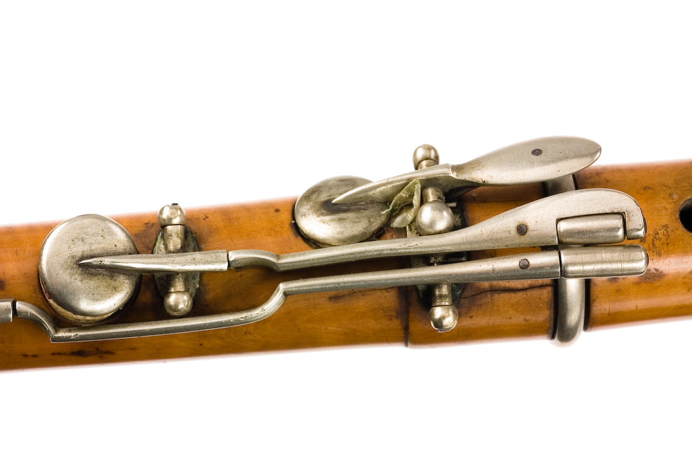 Tvärflöjt i buxbom med silverringar. 5 delar. C-fot. Kvadratiskt anblåsningshål. Tydliga märken efter användning vid anblåsnings- och fingerhål. 10 klaffar med kullagring, fästa i fastskruvade plattor. Klaffarnas plattor är runda. Klaffhålen har monterade metallrör.