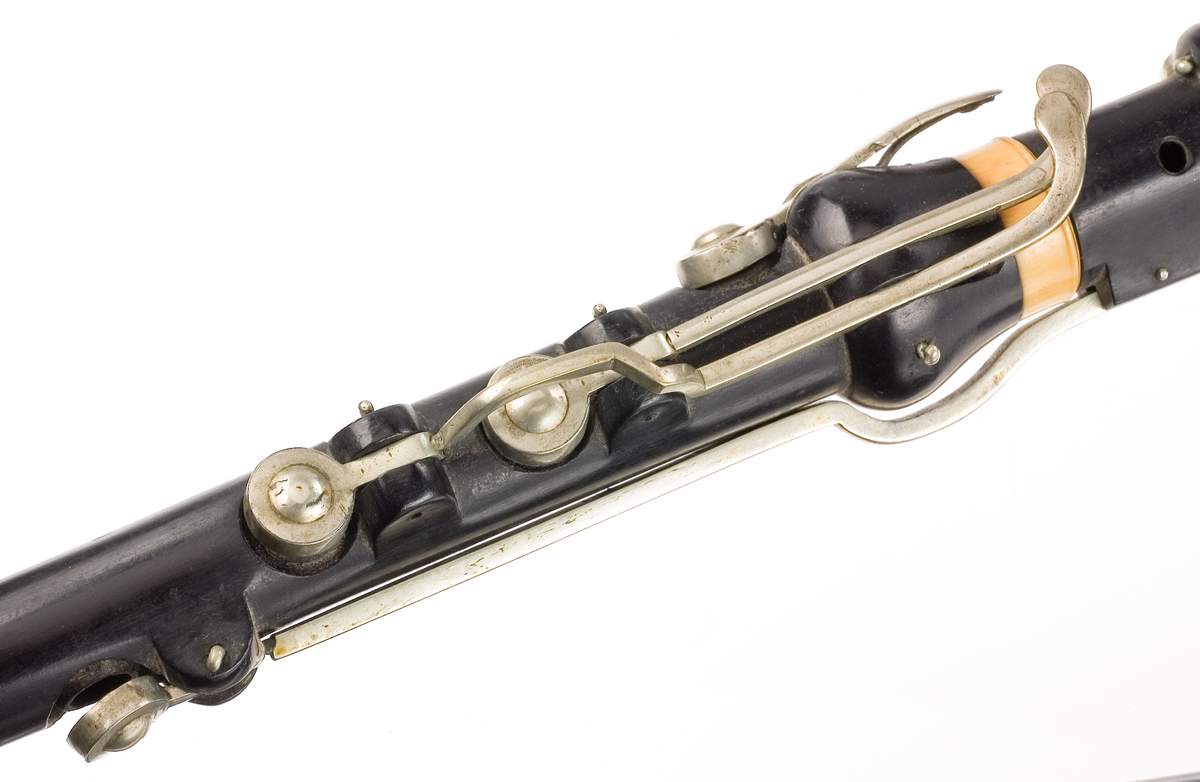 Tvärflöjt i ebenholts med ringar i elfenben. 5 delar. H-fot. Sprickor i munstycke och päron. 10 klaffar med bock- och vulstlagring. Klaffarna har runda, tämligen tjocka, plattor med en rundad upphöjning i mitten.