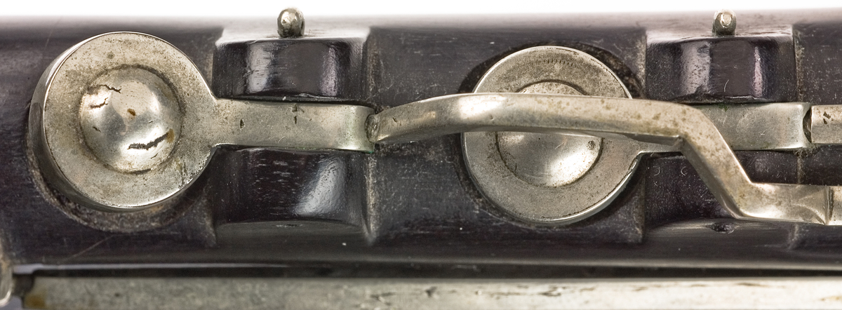 Tvärflöjt i ebenholts med ringar i elfenben. 5 delar. H-fot. Sprickor i munstycke och päron. 10 klaffar med bock- och vulstlagring. Klaffarna har runda, tämligen tjocka, plattor med en rundad upphöjning i mitten.