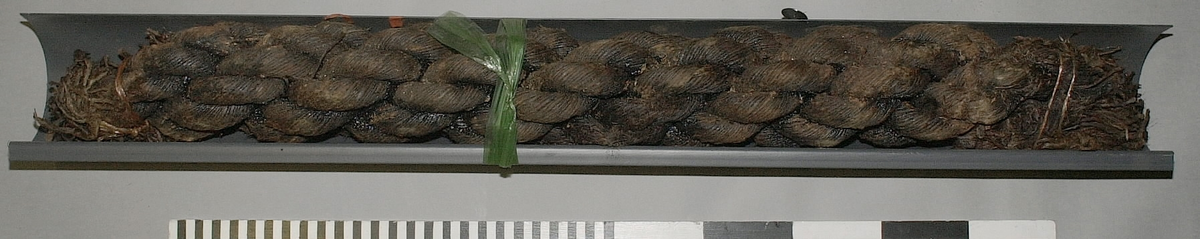 Tågvirke.
Del av grovt tågvirke till ankarkabeln.
S-slagen, tjärad del av ankarkabel, uppbyggd av tre Z-slagna trossar. Kabeln är skadad/fransig i ändarna och ligger i en skyddsränna av plast.