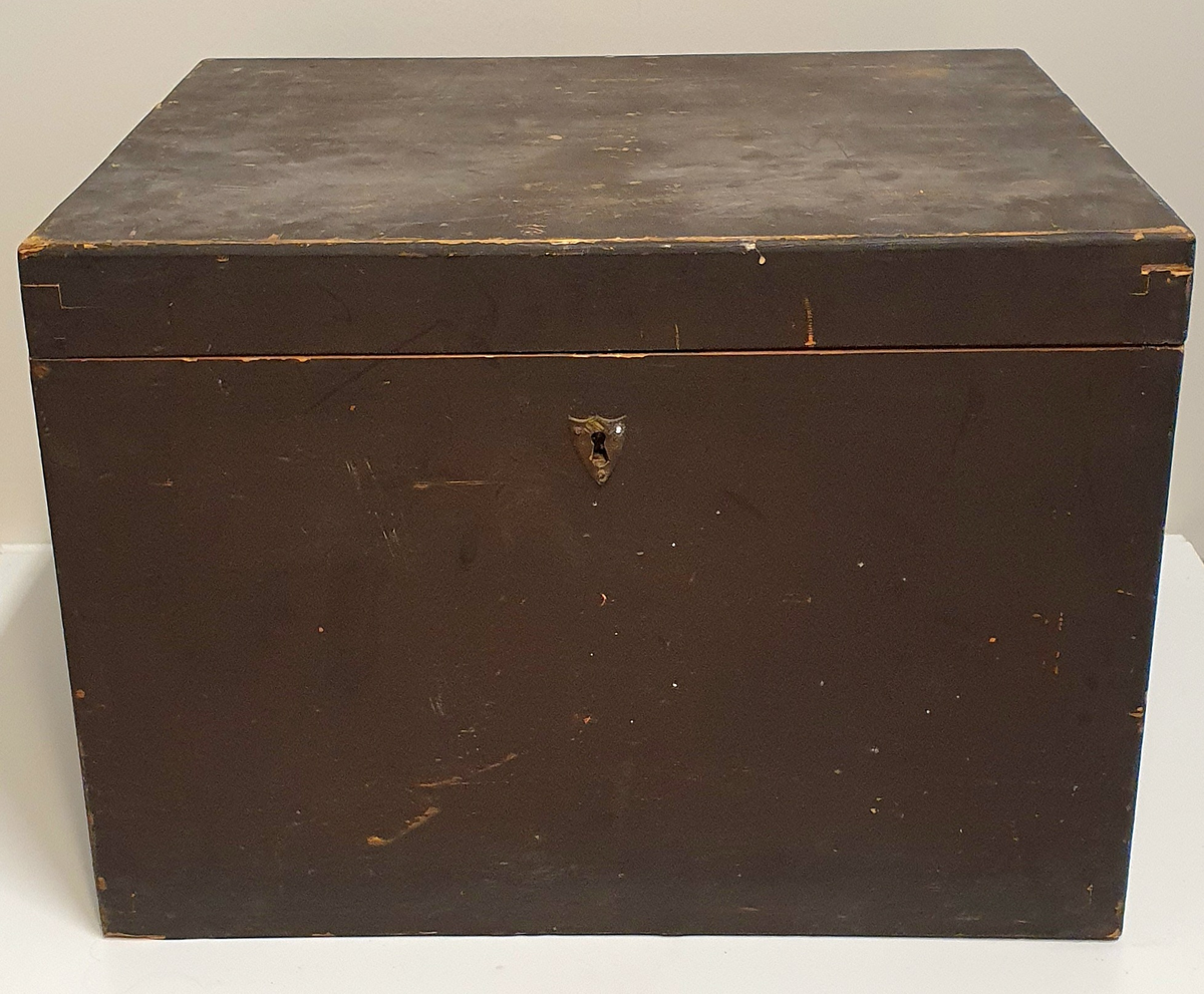 Stor kasse av tre med plass til seks hulmål i messing og tre glassplater. 

B: 20L
C: 5L
D: 1L
E: 0,5L
F: 0,2L
G: 0,1LL
H: 0,05L