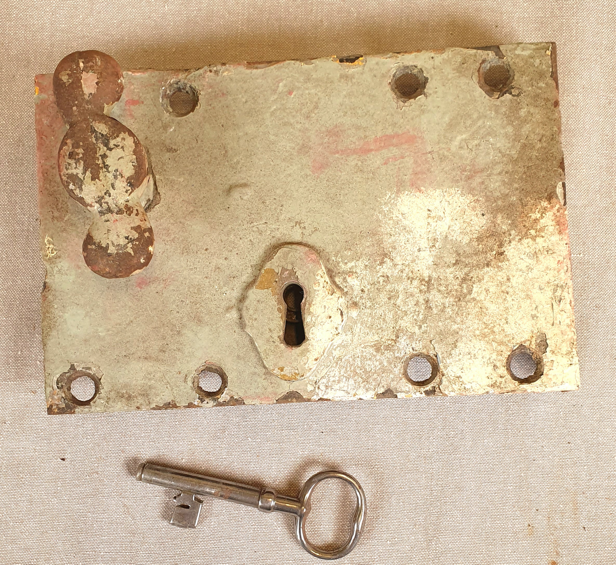 Seks dørlåser av jern. Alle låsene har nøkkelhull og dørvrider. Rammen er tilnærmet kvadratisk og har også hull for feste, samt en list på to paralelle sider, der en mangler. Har en tilhørende nøkkel. Det følger med en ramme i jern i samme stil, trolig til en dørluke.