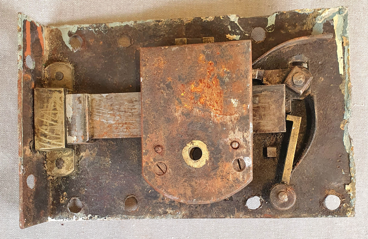 Seks dørlåser av jern. Alle låsene har nøkkelhull og dørvrider. Rammen er tilnærmet kvadratisk og har også hull for feste, samt en list på to paralelle sider, der en mangler. Har en tilhørende nøkkel. Det følger med en ramme i jern i samme stil, trolig til en dørluke.