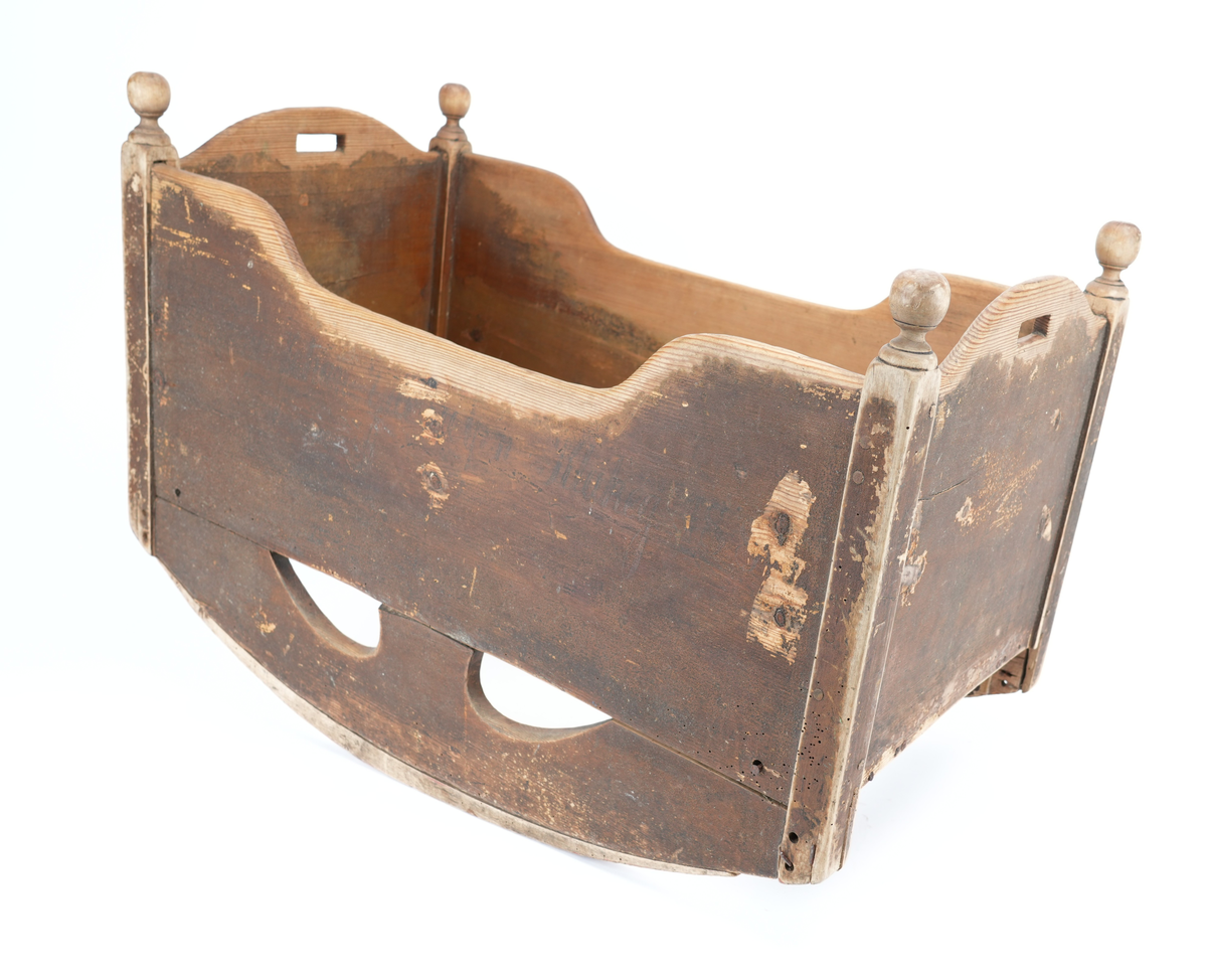 Brunmåla vugge til barn. Vangane er langsgåande slik at barnet vert vugga fram og tilbake, ikkje høgre til venstre. Kvar av dei fire hjørnestolpane har treknottar øvst som dekor. Vugga mangla sengebotn. Små handtak øvst på kvar av dei to kortsidene. 