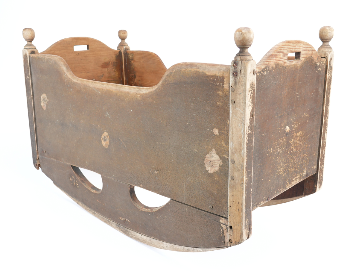 Brunmåla vugge til barn. Vangane er langsgåande slik at barnet vert vugga fram og tilbake, ikkje høgre til venstre. Kvar av dei fire hjørnestolpane har treknottar øvst som dekor. Vugga mangla sengebotn. Små handtak øvst på kvar av dei to kortsidene. 