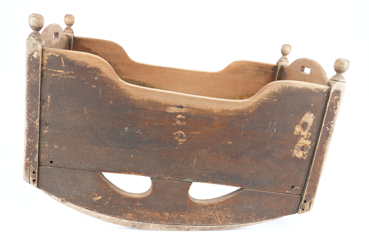 Brunmåla vugge til barn. Vangane er langsgåande slik at barnet vert vugga fram og tilbake, ikkje høgre til venstre. Kvar av dei fire hjørnestolpane har treknottar øvst som dekor. Vugga mangla sengebotn. Små handtak øvst på kvar av dei to kortsidene. 