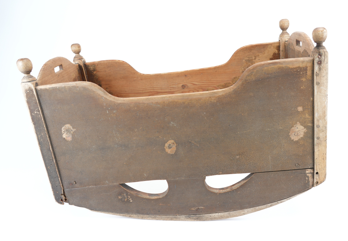 Brunmåla vugge til barn. Vangane er langsgåande slik at barnet vert vugga fram og tilbake, ikkje høgre til venstre. Kvar av dei fire hjørnestolpane har treknottar øvst som dekor. Vugga mangla sengebotn. Små handtak øvst på kvar av dei to kortsidene. 