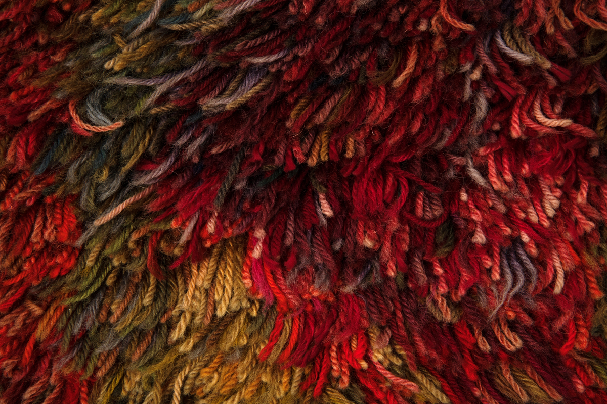 Rektangulær rye i ullfloss med rombemotiv. Tette rekker innknyttet langtrådet floss av løst tvunnet, tykt ullgarn med cirka 1 cm avstand mellom rekkene. Flossens hovedfarge er gullig (gult og nyanser av beige og grønt) med svake innslag av mønsterfargene; nyanser av rødt og blått. Disse er samlet i ujevne, rombiske figurer i rekker. En bred kant uten floss, i bunninnslagets gullige farge avslutter ryen oppe og nede.