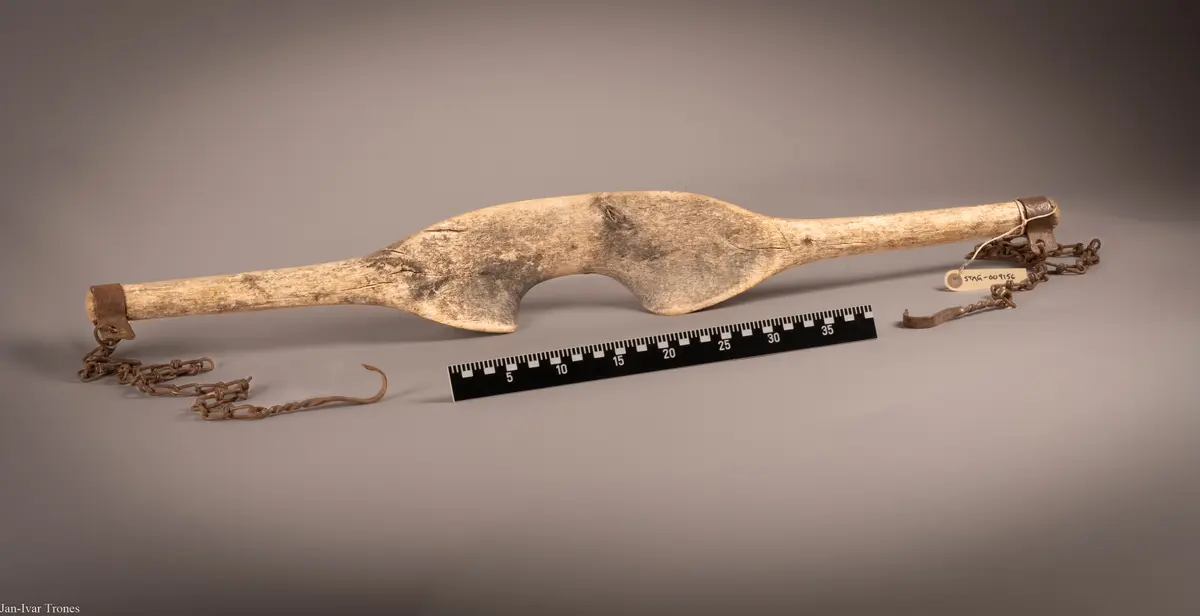 Børtre med stålbeslag og kjetting i begge ender. I endene av kjettingene er det kroker for å henge bøtter i.