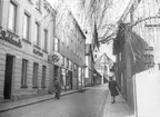 Ågatan västerut från Klostergatan med Domkyrkan i fonden. Till höger syns Ågatan 39 med det hus som 1953 monterades ned för flytt till Gamla Linköping och där det kallas Jungfru Lovisas gård. En man syns sopa gatan.
