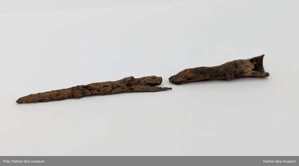 KLM 4737. Spjutspets av järn. Starkt förrostat fragment av spjutspets i två delar. Med hullingar, en avbruten, och holk med bevarad nit. Holken är skadat och avbruten från resten av spetsen.