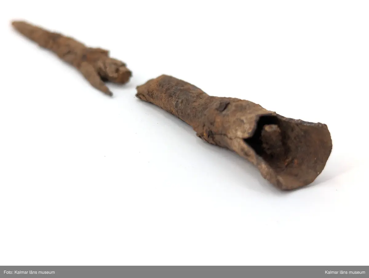 KLM 4737. Spjutspets av järn. Starkt förrostat fragment av spjutspets i två delar. Med hullingar, en avbruten, och holk med bevarad nit. Holken är skadat och avbruten från resten av spetsen.