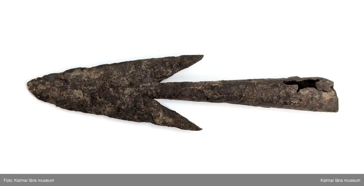 Järnålder. Bred spjutspets av järn med hullingar. Rund holk, något skadad.