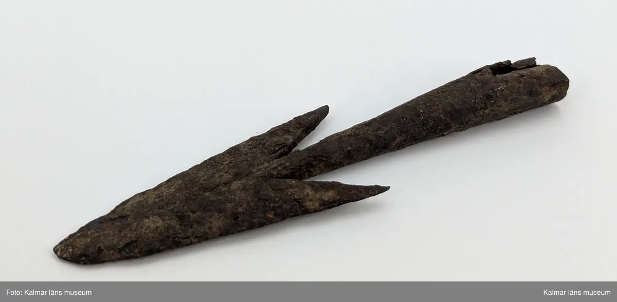 Järnålder. Bred spjutspets av järn med hullingar. Rund holk, något skadad.