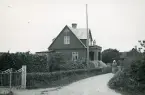 En sekelskiftesvilla med glasveranda och balkong, inramad av en uppvuxen häck samt en grind, Torekov i Skåne 1922.