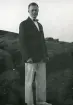 Tandläkare Gunnar Högberg uppklädd i kavaj och fluga stående på en klippa i Torekov, Skåne 1922.